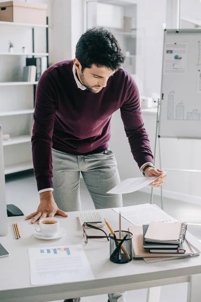 Handsome designer in burgundy sweater reading documents in office — Stock Photo