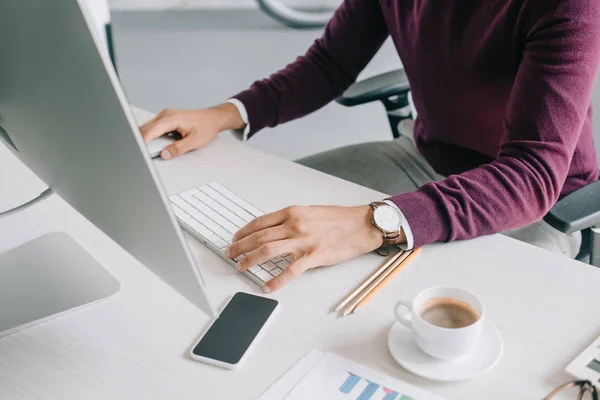 Cropped image of businessman in burgundy sweater working at computer in office — Stock Photo