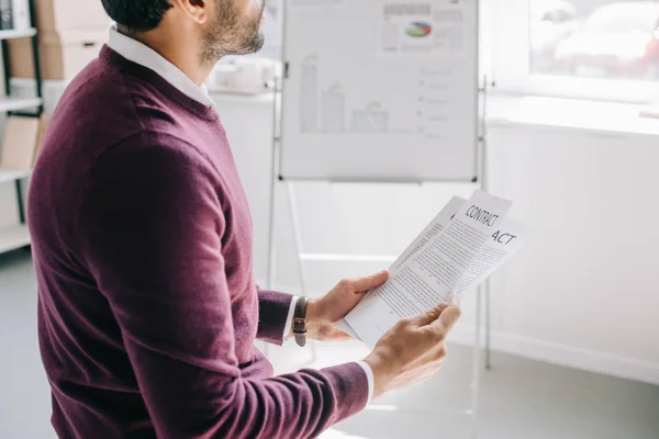 Image recadrée de designer en chandail bordeaux tenant contrat dans le bureau — Photo de stock