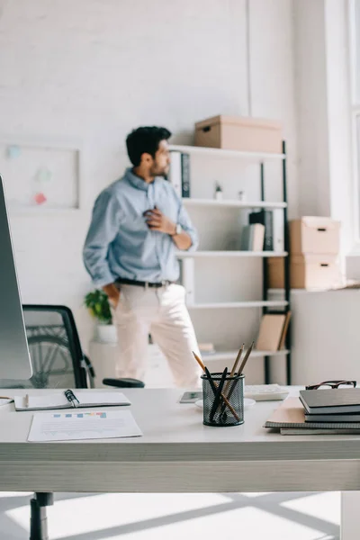 Pensive architect looking away with pencils in pen holder on foreground in office — Stock Photo