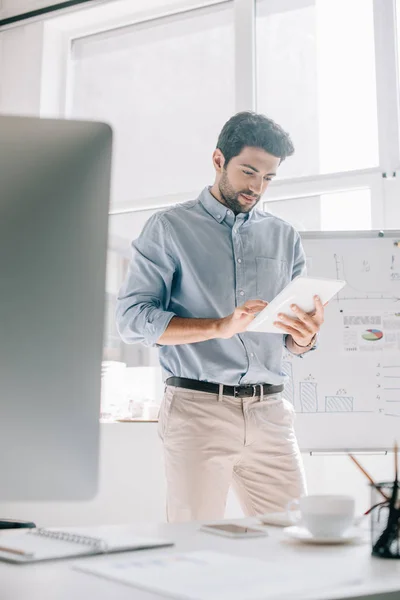 Arquitecto guapo en camisa azul usando tableta en la oficina - foto de stock