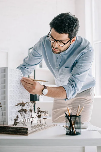 Arquiteto bonito trabalhando com modelo de arquitetura na mesa no escritório — Fotografia de Stock