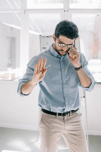Gutaussehender Architekt spricht per Smartphone und gestikuliert im Büro — Stockfoto
