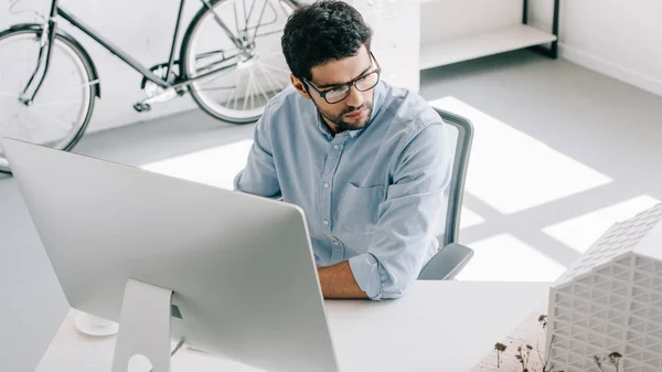 Handsome architect using computer and looking at architecture model in office — Stock Photo