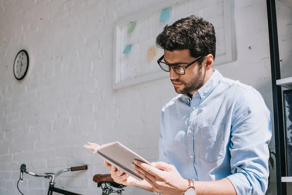 Gutaussehender Architekt mit Brille liest Buch im Büro — Stockfoto