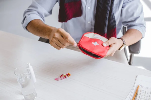 Cropped image of sick manager in scarf open first aid kit in office — Stock Photo