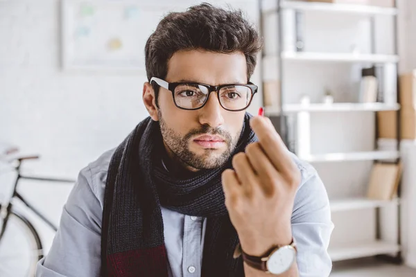 Sick manager in scarf and glasses looking at pill in office — Stock Photo