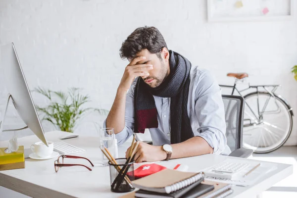 Kranker Manager im Schal berührt Stirn und sitzt im Büro am Tisch — Stockfoto