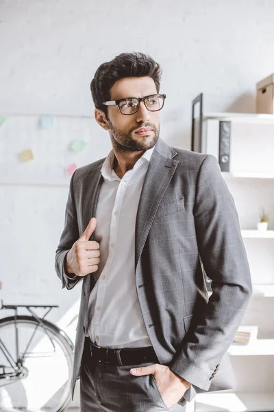 Schöner Geschäftsmann im grauen Anzug schaut im Büro weg — Stockfoto