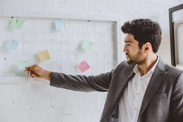 Handsome businessman taking sticker from task board in office — Stock Photo