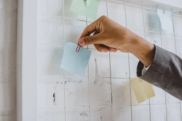 Imagem cortada de empresário tomando papel adesivo do quadro de tarefas no escritório — Fotografia de Stock