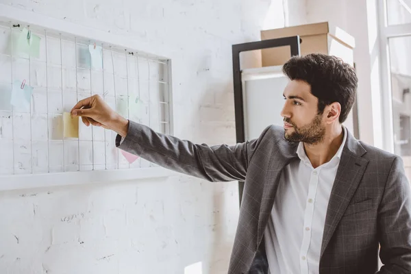 Hombre de negocios guapo poner pegatina de papel en el tablero de tareas en la oficina - foto de stock