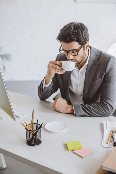 Bonito empresário beber café no escritório — Fotografia de Stock