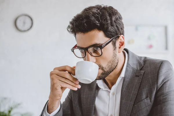 Porträt eines gutaussehenden Geschäftsmannes, der im Büro Kaffee trinkt — Stockfoto