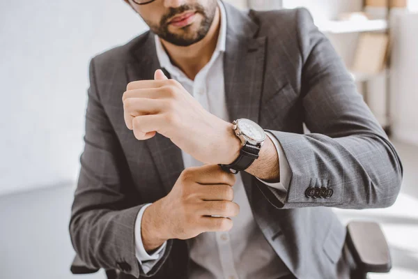 Cropped image of businessman wearing wristwatch in office — Stock Photo