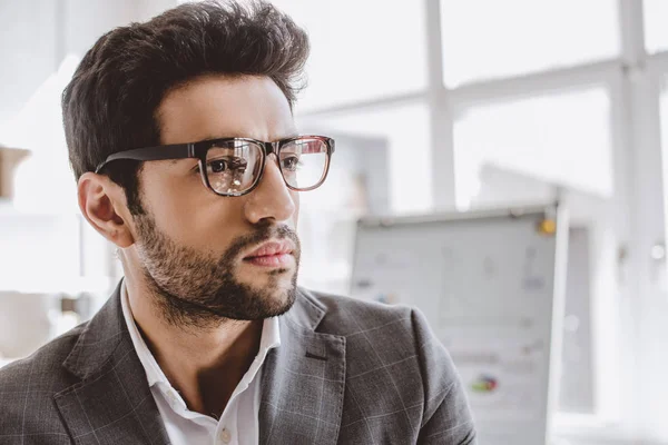 Retrato de empresário bonito em óculos olhando para longe no escritório — Fotografia de Stock