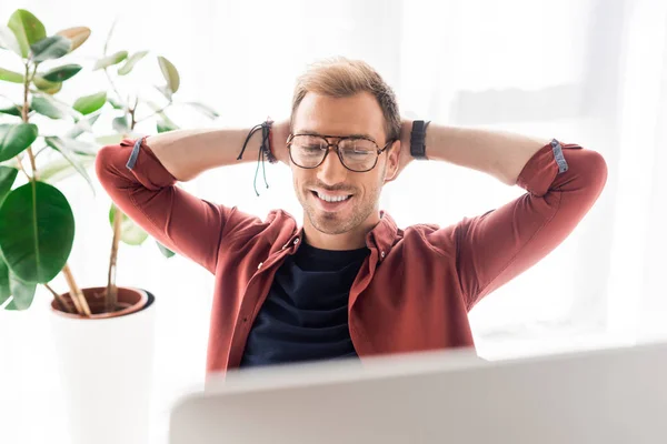 Homme d'affaires souriant avec les mains derrière la tête dans le bureau moderne — Photo de stock