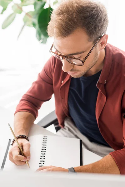 Homem de negócios casual em óculos escrevendo em notebook — Fotografia de Stock