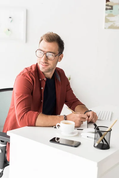 Hombre de negocios guapo en gafas mirando hacia otro lado en la oficina moderna - foto de stock