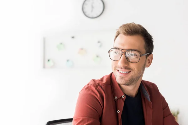 Homme d'affaires souriant dans des lunettes détournant les yeux — Photo de stock