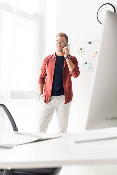 Бизнесмен разговаривает на смартфоне в современном офисе — стоковое фото