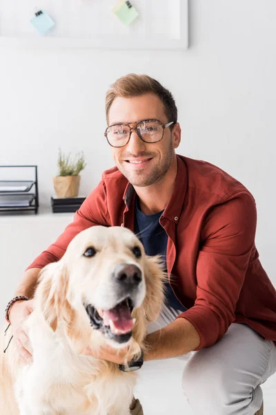 Homem de óculos abraçando golden retriever e olhando para a câmera — Fotografia de Stock