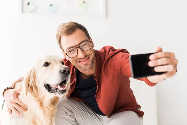 Щасливий чоловік бере селфі на смартфон з милим золотим собакою-ретривером — стокове фото