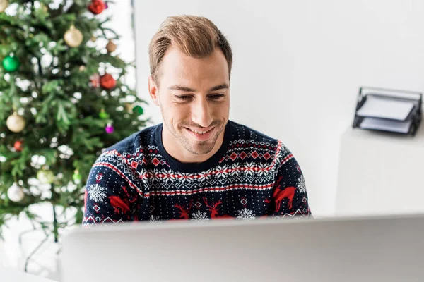 Geschäftsmann im Weihnachtspulli mit Computer im modernen Büro — Stockfoto