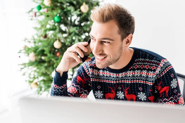 Geschäftsmann im Weihnachtspulli telefoniert mit Smartphone in der Nähe des Weihnachtsbaums — Stockfoto