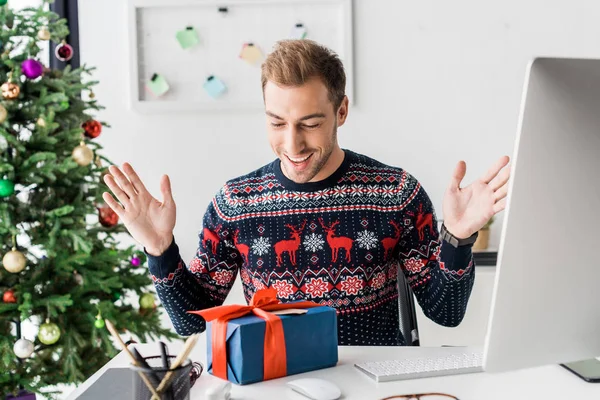 Überraschter Geschäftsmann im Winterpullover schaut auf Weihnachtsgeschenkschachtel — Stockfoto