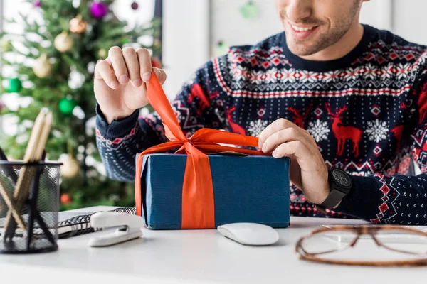Cropped view of businessman in christmas sweater opening gift box — Stock Photo