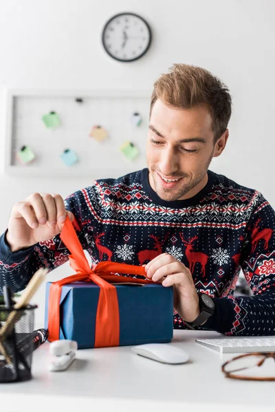 Homme d'affaires heureux dans la boîte cadeau d'ouverture de pull de Noël — Photo de stock