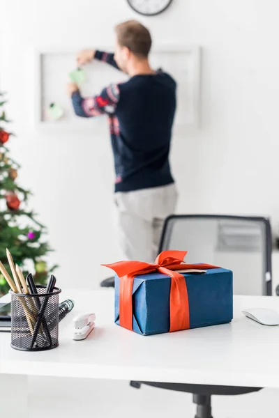 Рождественская подарочная коробка на столе и бизнесмен, работающий на заднем плане — стоковое фото