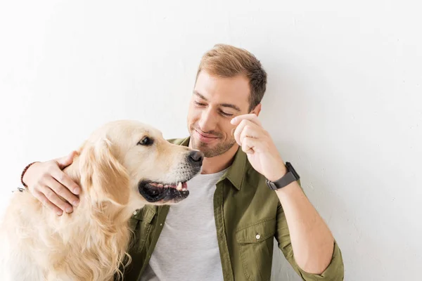 Uomo accarezzando cane golden retriever contro muro bianco — Foto stock