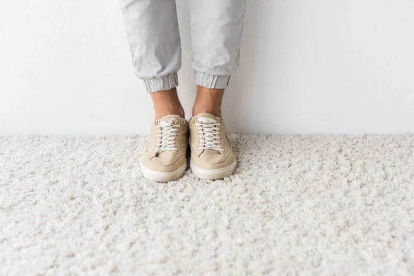 Vue de la section basse de l'homme à la mode sur tapis beige — Photo de stock