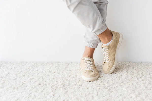 Vista recortada de un hombre casual de pie sobre una alfombra beige - foto de stock