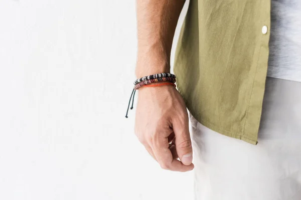 Cropped view of male hand with bracelets against white wall — Stock Photo