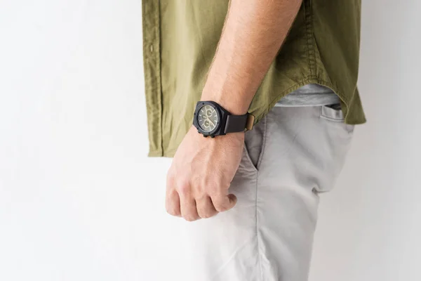 Vista ritagliata della mano maschile con orologio da polso contro parete bianca — Foto stock