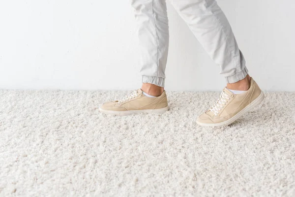 Ausgeschnittene Ansicht von Männerbeinen auf Teppich gegen weiße Wand — Stockfoto