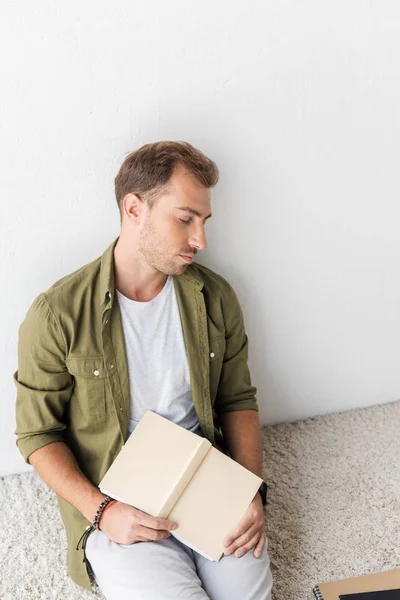 Tired man with notebook sleeping on carpet near wall — Stock Photo