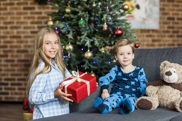 Милые счастливые дети с подарком, улыбающиеся на камеру — стоковое фото