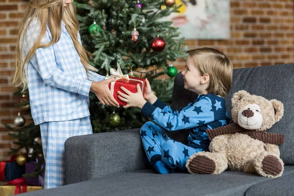 Schnappschuss von Schwester präsentiert Weihnachtsgeschenk an entzückenden glücklichen Bruder — Stockfoto