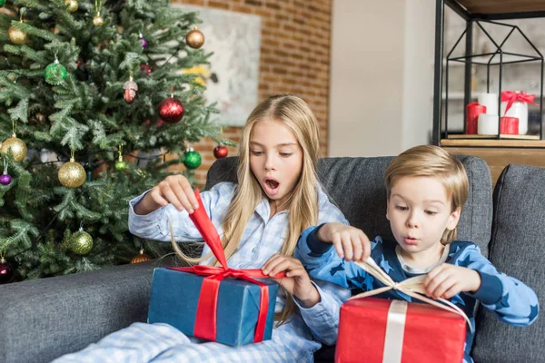 Здивовані діти в піжамі відкривають різдвяні подарунки — стокове фото