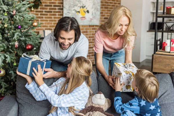 Parents présentant des cadeaux de Noël à des enfants heureux en pyjama — Photo de stock