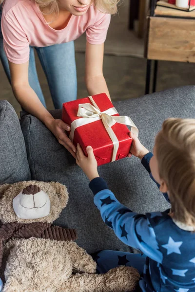 Tiro cortado de mãe apresentando presente de Natal para o pequeno filho — Fotografia de Stock