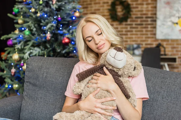 Красива молода жінка з закритими очима обіймає плюшевого ведмедя в різдвяний час — стокове фото