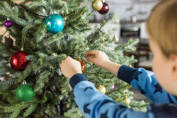 Plan recadré de l'enfant en pyjama décorant arbre de Noël — Photo de stock