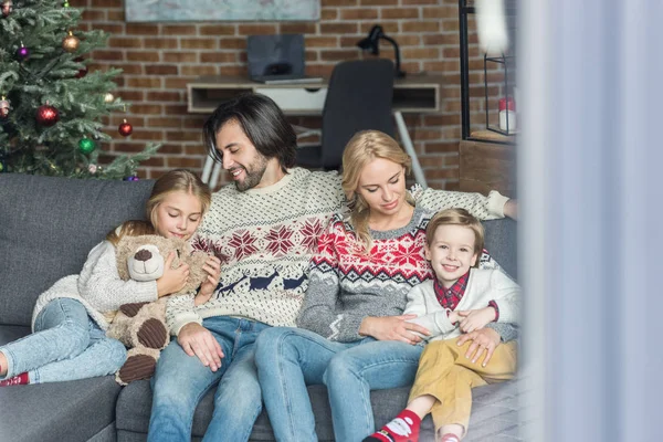 Happy family with two children sitting together on couch at christmas time — Stock Photo