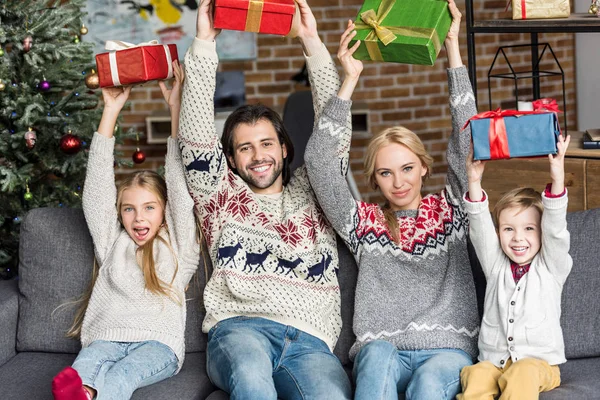 Familia feliz con dos niños sosteniendo regalos de Navidad y sonriendo a la cámara - foto de stock