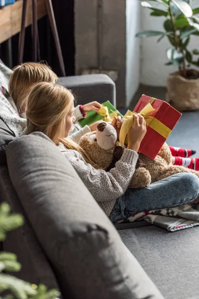 Высокий угол зрения детей, сидящих на диване и открытие рождественских подарков — стоковое фото
